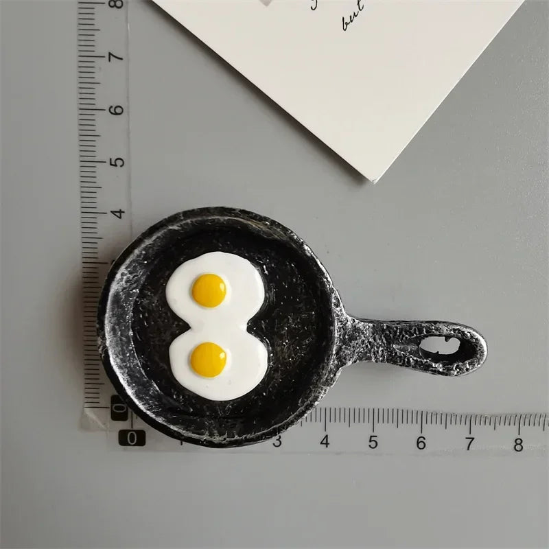 A black food-shaped magnet resembling an egg is placed next to a ruler.