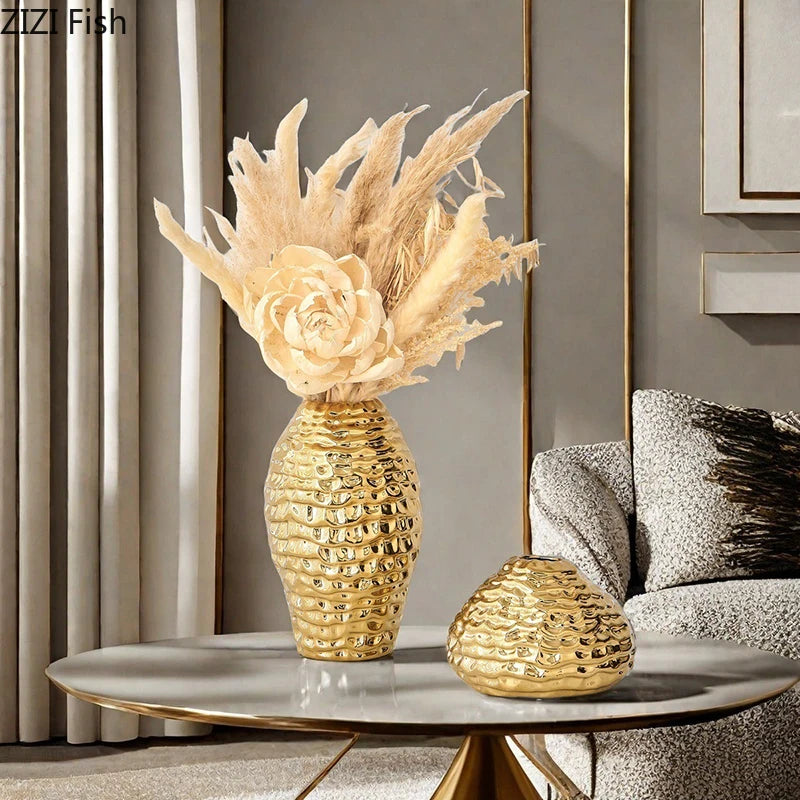 A golden wrinkle ceramic tabletop vase filled with dried grasses on a gray table.