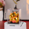 A golden solar-powered waving lucky cat figurine displayed in a clear acrylic box.