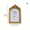 Gold-framed vintage resin photo frame with a white background and floral accent