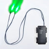 A black wire connects an LED glowing green eye to a remote control device with timer functions.