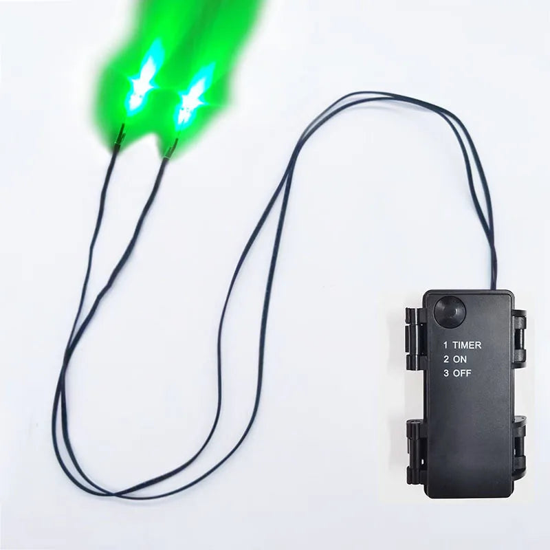 A black wire connects an LED glowing green eye to a remote control device with timer functions.
