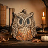 A vintage owl-shaped pumpkin decor featuring natural wood tones and feathers sits on a wooden surface.