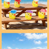 A collection of glow-in-the-dark resin duck figurines with colorful hats placed on a wooden deck near the ocean.