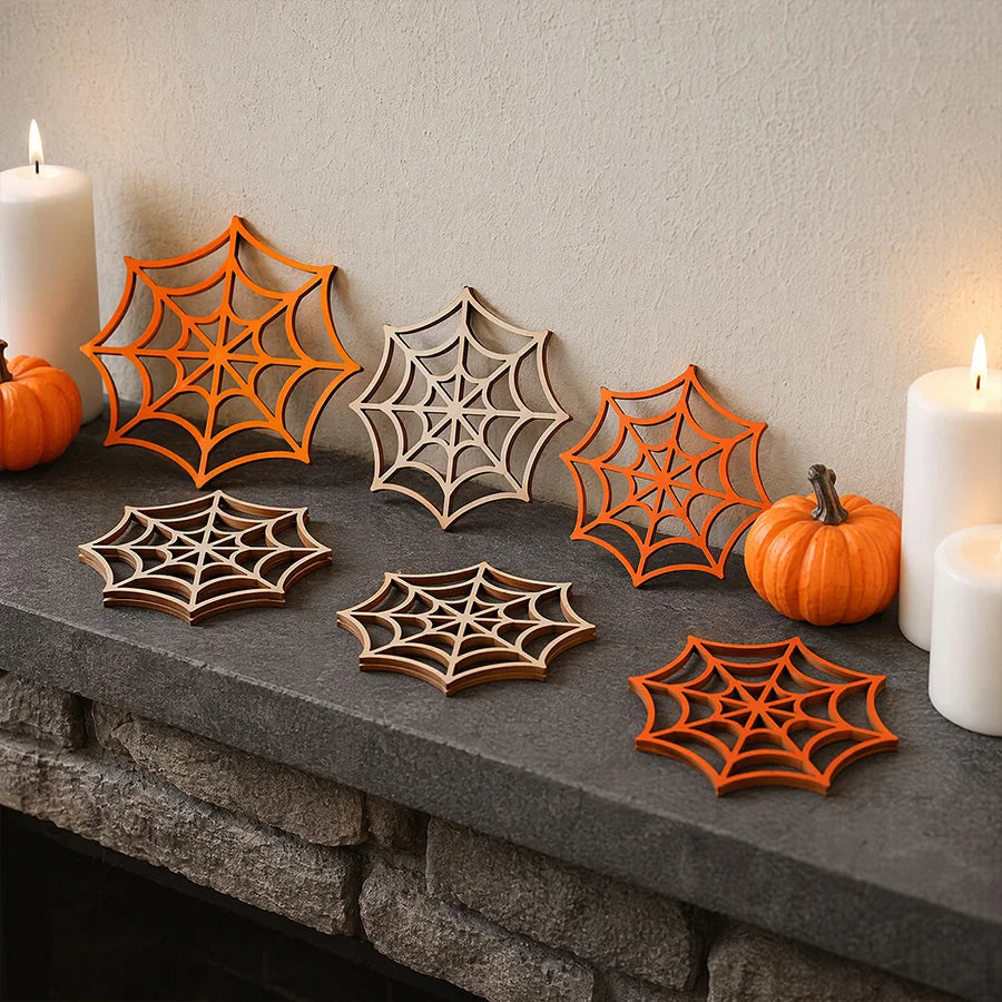 A collection of orange and natural wood wooden spider web ornaments displayed on a dark stone ledge next to white candles.