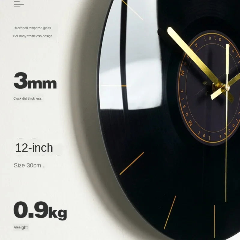 A close-up of a black wall clock with a gold-toned face and hands, showing specifications like 3mm thickness and 12-inch size