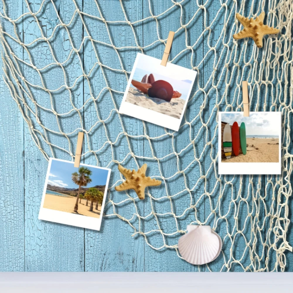 Adornos de redes de pesca decorativas con estrellas de mar y escenas de playa colgados en una superficie de madera azul