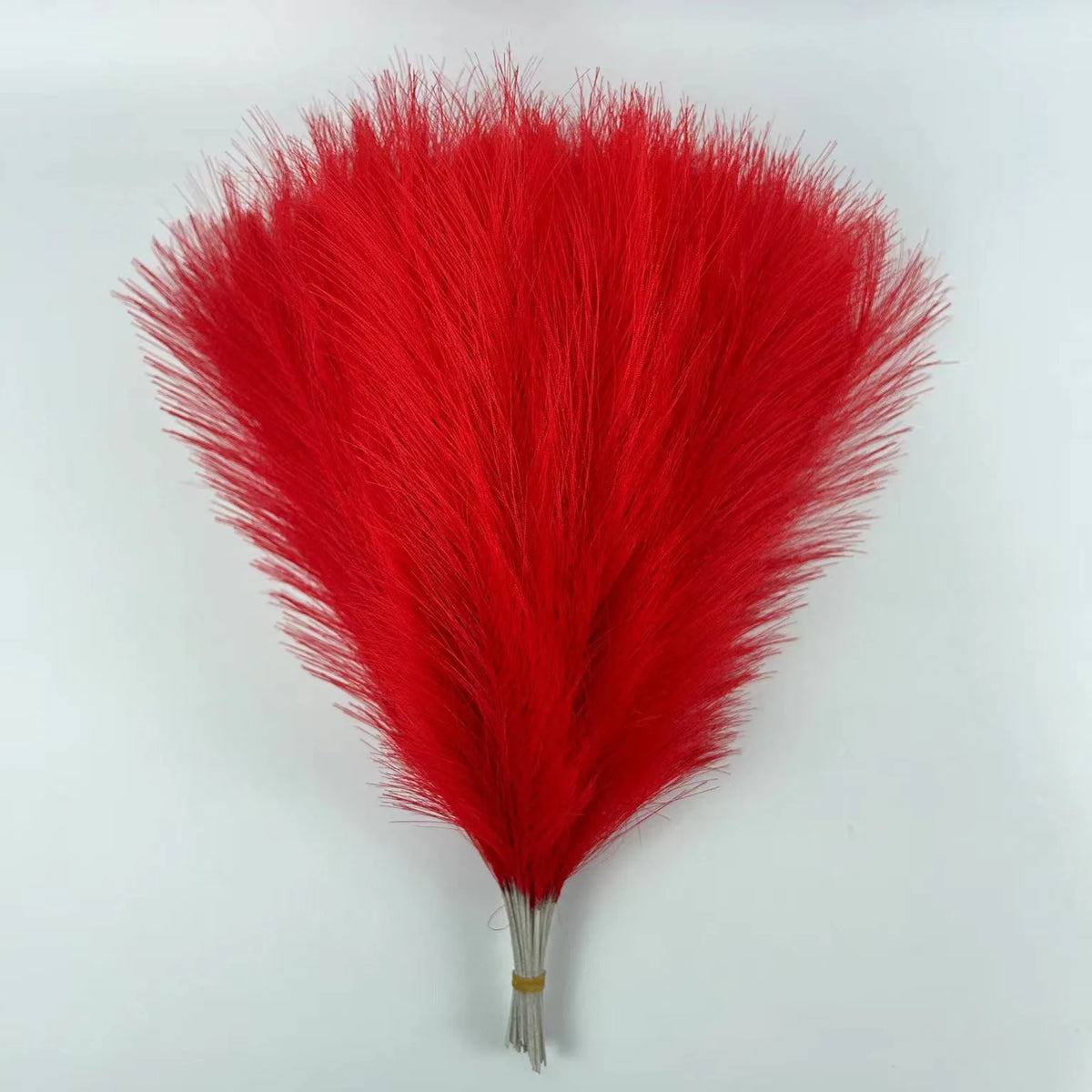 A vibrant red artificial pampas grass plume used for boho wedding and home decor.