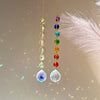 A delicate necklace featuring a string of colorful crystal beads and a faceted clear pendant.