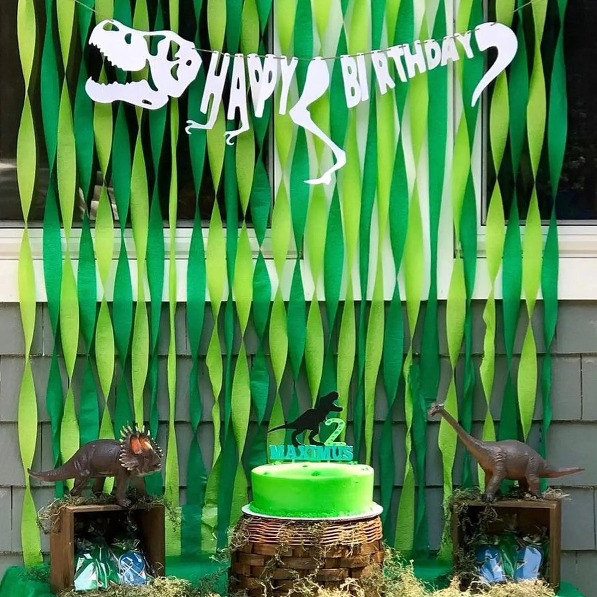 Grüne Crêpepapier-Girlanden in Dinosaurierform als Banner für eine Geburtstagsfeier