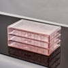 Clear acrylic jewelry organizer with three drawers displayed on a reflective surface.