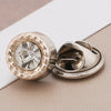 A close-up of a gold-toned rhinestone button with a clear center, shown against a light background.