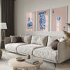 A modern living room features a light sofa, wooden coffee table, and framed art prints with blue and pink tones.