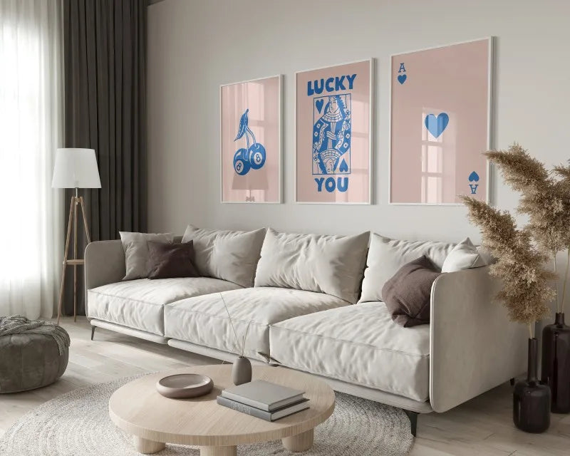 A modern living room features a light sofa, wooden coffee table, and framed art prints with blue and pink tones.