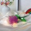 A translucent pink rose flower building block placed on white fabric with a rainbow light effect.