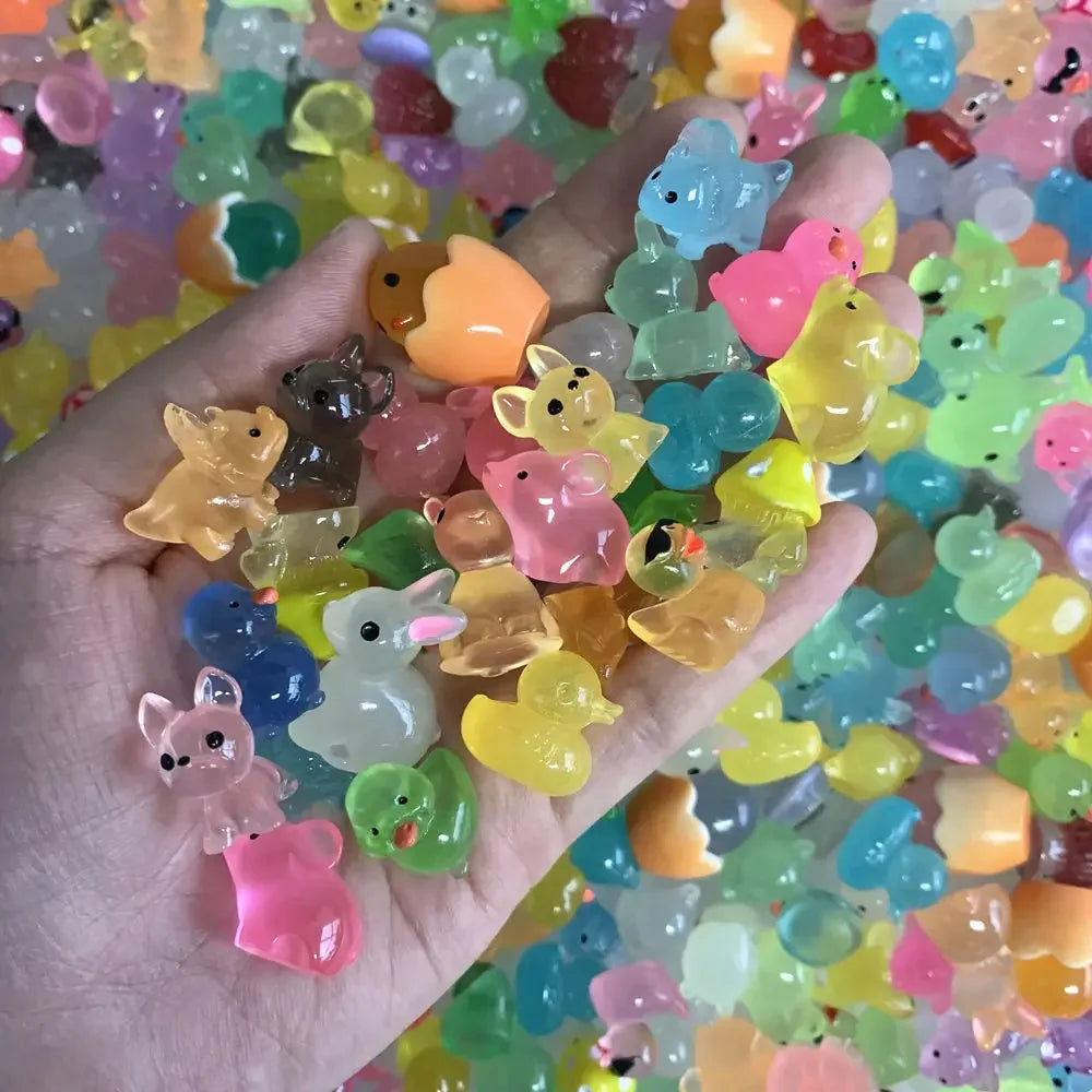 A hand holds a large quantity of colorful luminous resin animal figurines for aquarium decor.