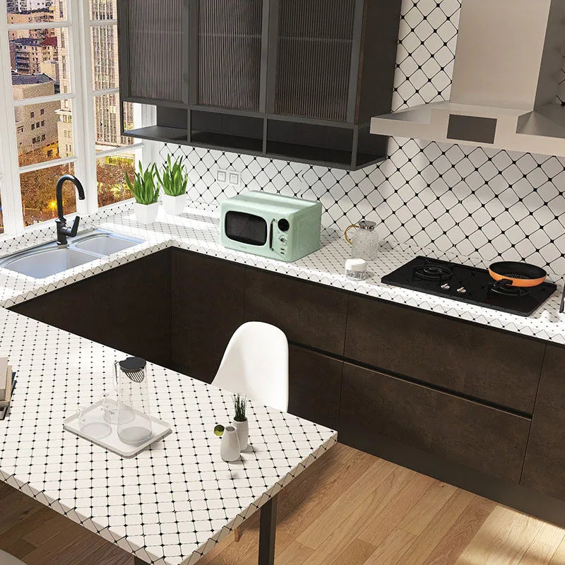 A modern kitchen featuring dark cabinetry, a speckled countertop, and a backsplash with a diamond pattern.