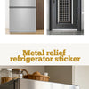 A close-up of a stainless steel refrigerator featuring an embossed metal magnet depicting a scenic Switzerland landscape.