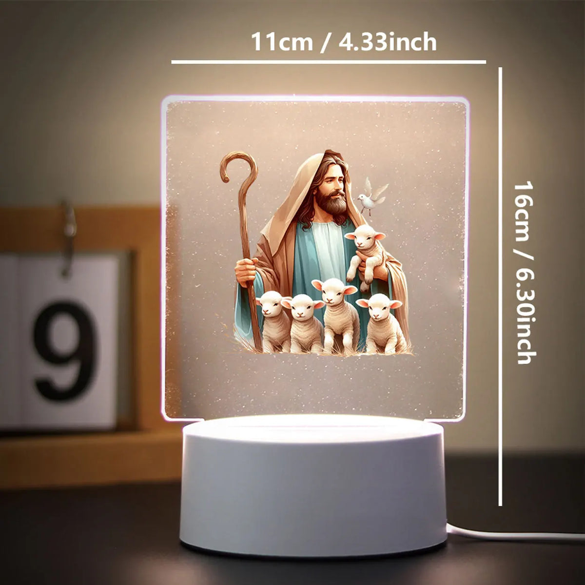 A 3D LED night light featuring a Jesus figure with lambs, displayed on a white base.