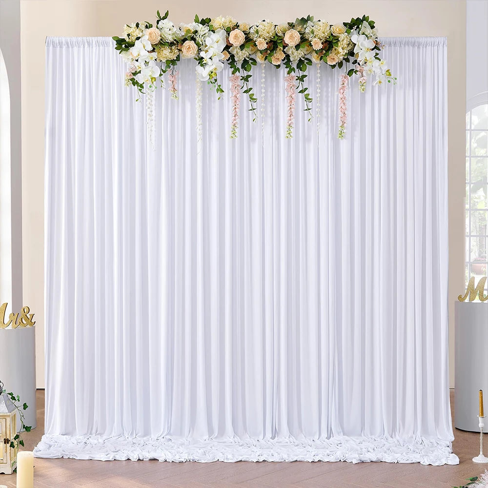 White sheer polyester backdrop curtains decorated with a floral garland for an event or photo shoot.