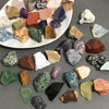 Assorted natural raw crystal stones and healing minerals displayed on a white plate.