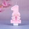 A pink glittery number one birthday candle decorated with a pink bow against a light purple background.