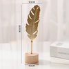 A vertical golden ginkgo leaf metal decorative sculpture standing on a wooden base.