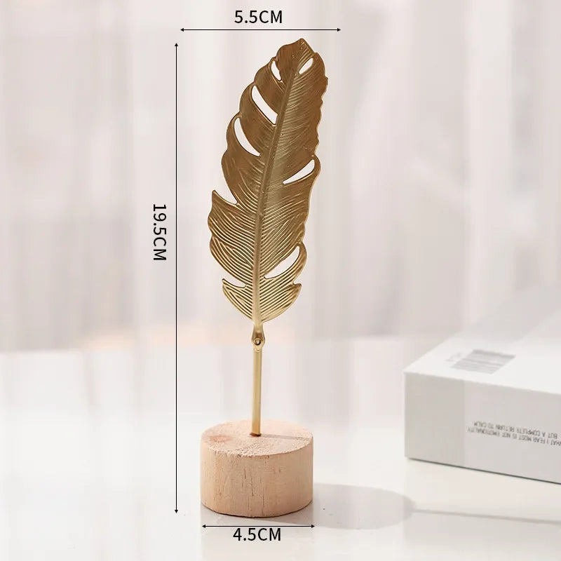 A vertical golden ginkgo leaf metal decorative sculpture standing on a wooden base.