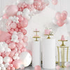 A pink and white latex balloon arch display featuring balloons, pink and white, arranged on a white marble background.