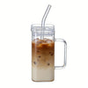 A tall glass mug filled with iced coffee, featuring a clear lid and a metal handle.