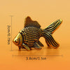 Retro brass goldfish statue with textured scales shown against an orange background.