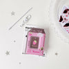 A pink plastic milk bottle photo keychain featuring a strawberry design and a small charm.