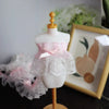 A white mannequin display featuring a delicate pink bow ruffle made of embroidery lace trim.