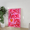 Pink canvas wall art featuring the text MORE AMOR POR FAVOR in bright red script on a white background