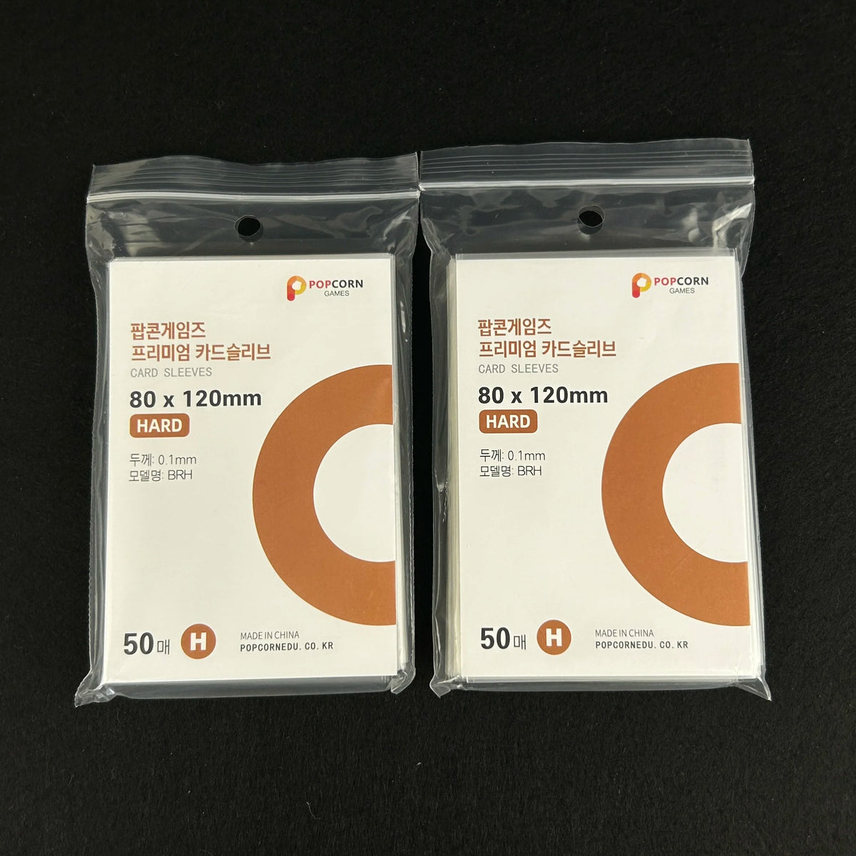 Two sealed packages of POPCORN GAMES premium card sleeves in a clear plastic bag with orange cards.