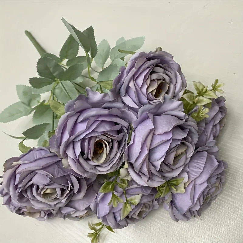 A bouquet of nine realistic purple silk roses with green leaves.