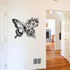 Black metal butterfly wall decor featuring an intricate floral pattern mounted on a white wall.