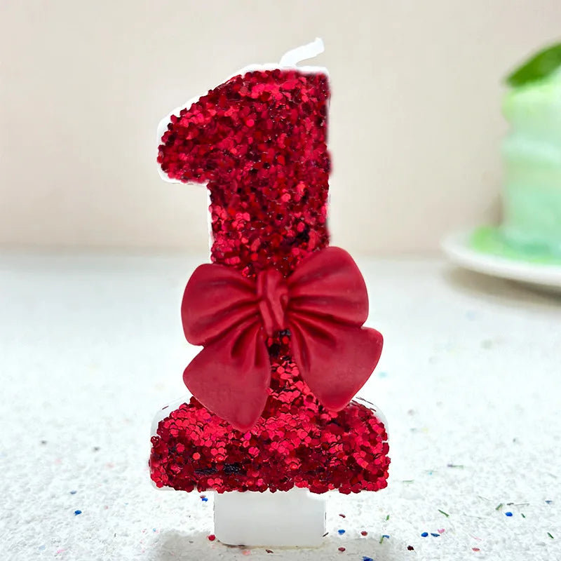 A red glitter number one candle decorated with a deep red bow, set against a white background.