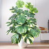 Artificial monstera plant with silk green and white leaves displayed in a white pot.