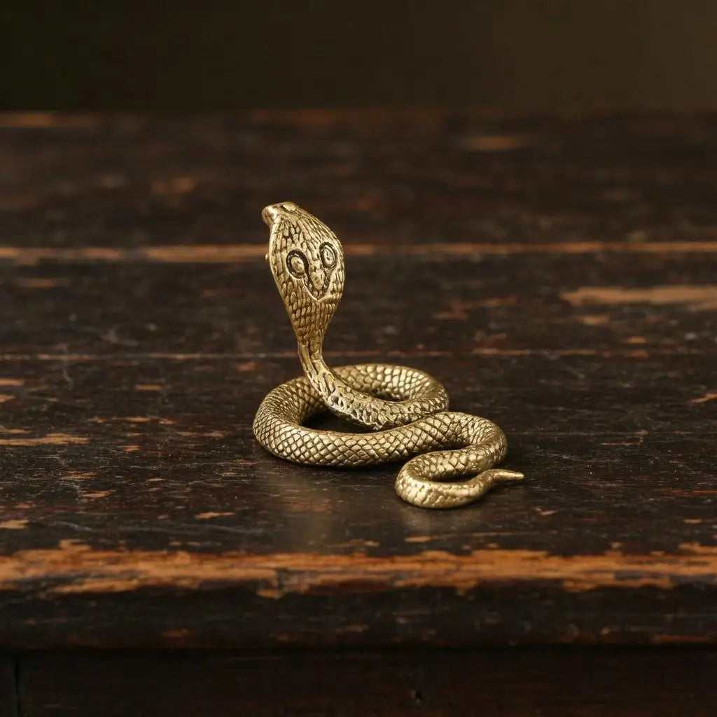 A detailed brass snake sculpture with an Art Deco design resting on a dark wooden surface.