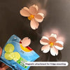 A light pink cherry blossom flower is shown next to a blue package for magnetic attachment for fridge mounting.
