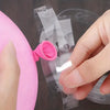A hand is placing a pink balloon onto a clear plastic strip for a double-hole balloon garland.