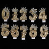 A set of gold glitter number cake toppers featuring rhinestone bows for the numbers 0 through 8.