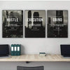 A set of three framed black and white motivational posters titled Hustle Execution and Grind displayed on a light gray wall a