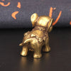 Antique bronze elephant figurine with a detailed collar, resting on a dark surface.