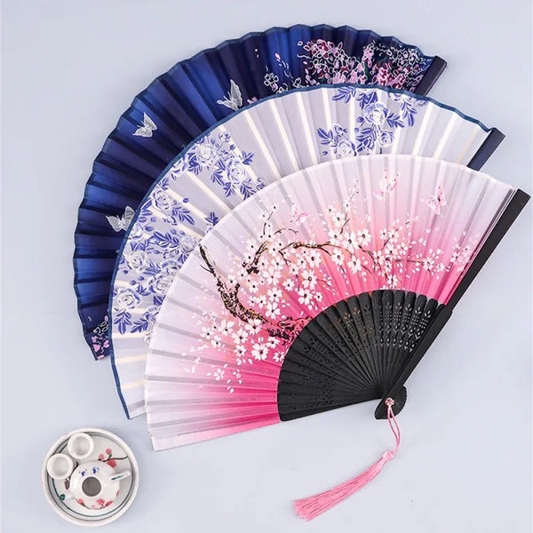 A set of vintage silk folding hand fans in shades of blue, pink, and black.