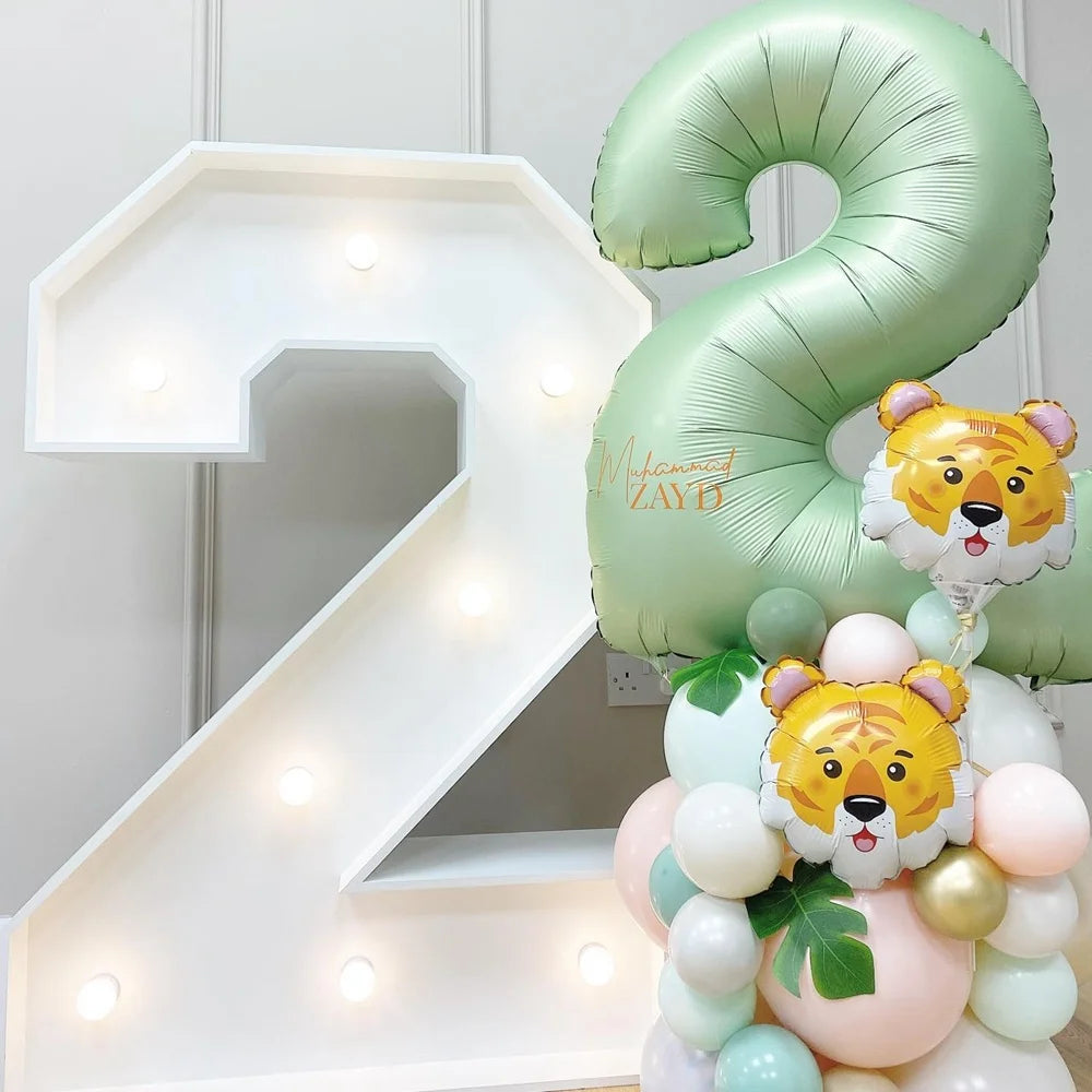 A large white number 2 made of light-up acrylic and a green foil balloon shaped like a number 2 with a tiger face