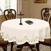 Elegant white tablecloth with gold embroidery set on a dark wooden table.