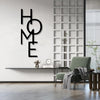 Black metal word art spelling HOME mounted on a white wall with a glass grid partition and a green armchair.