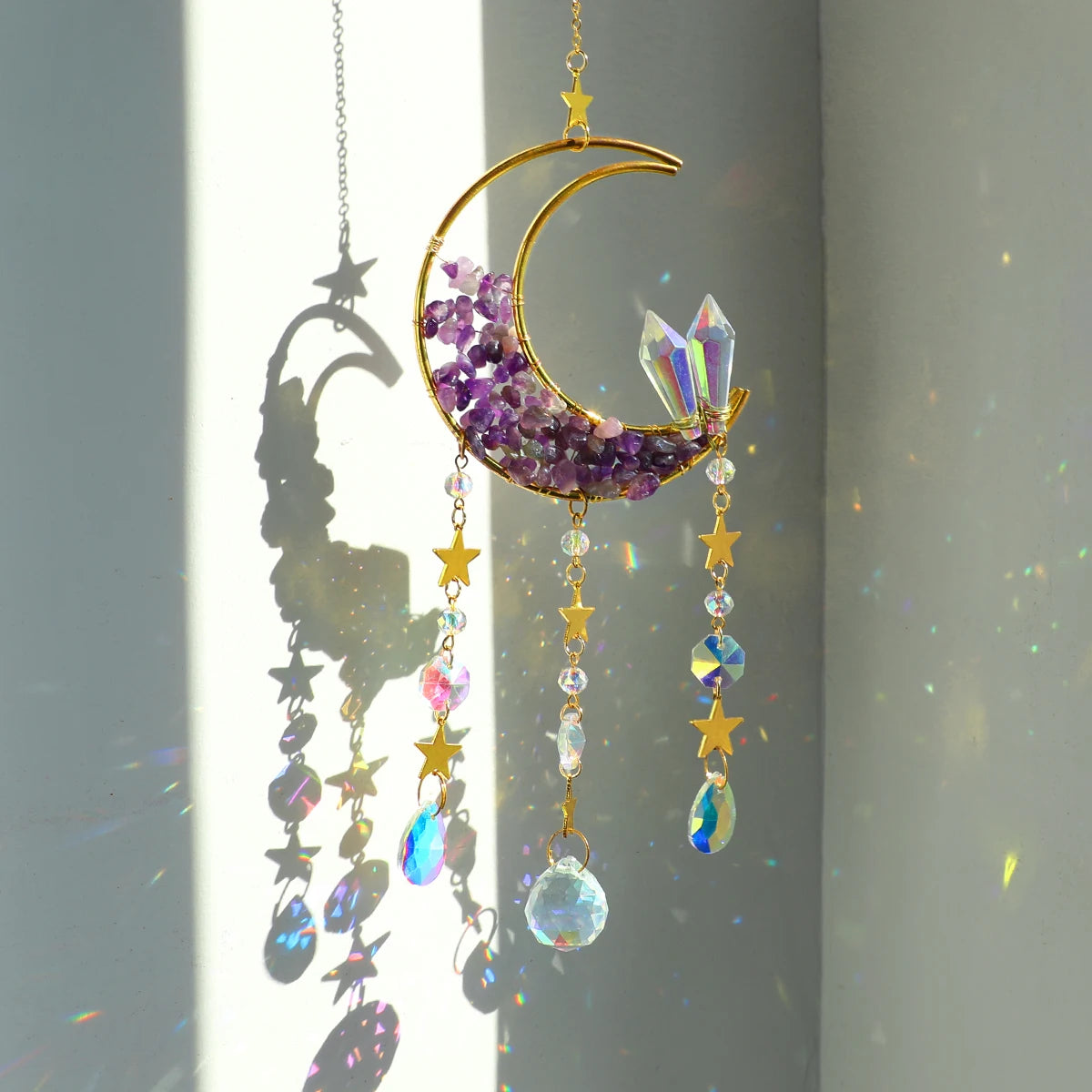 A gold crescent moon dreamcatcher hangs, featuring purple crystals and dangling iridescent charms.